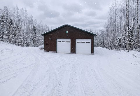 Dark brown garage with two white doors in snowy landscape