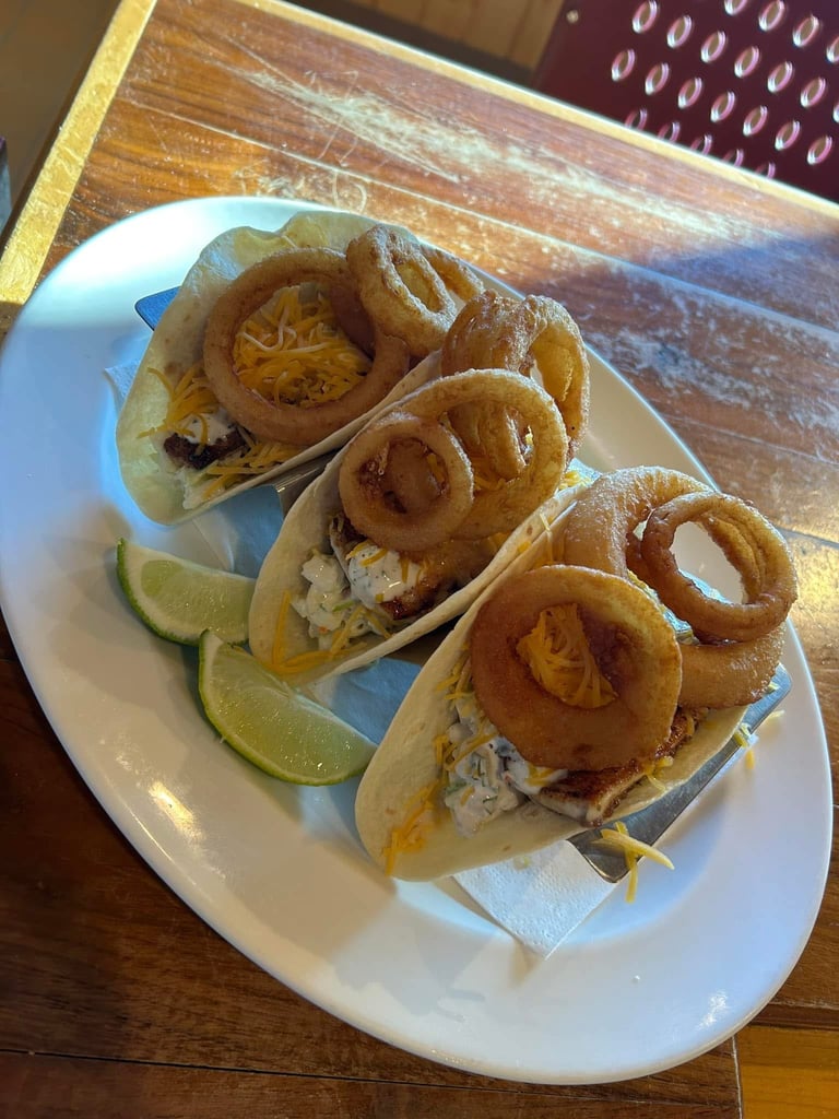 Fish tacos with fried onion rings and lime wedges