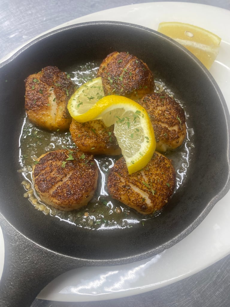 Golden-brown breaded meatballs simmering in lemon sauce in a black cast iron skillet with lemon slices