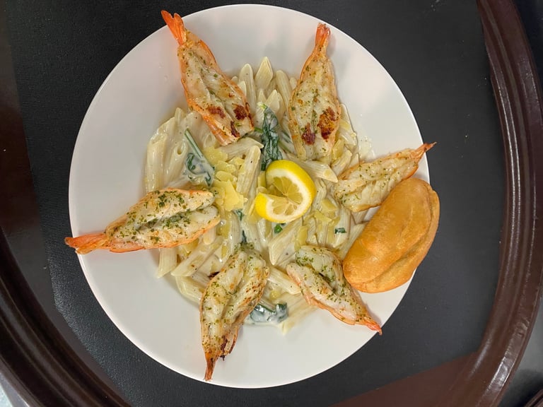 Plate of garlic butter shrimp arranged in a star pattern with pasta and lemon slice garnish
